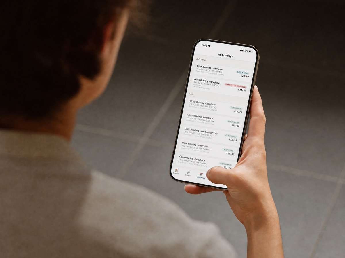 A customer holding their phone, viewing their bookings in your branded bowling-center app